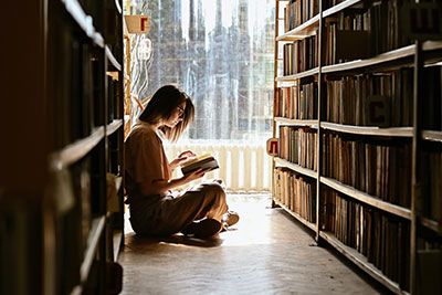 Femme dans une bibliothèque hypnotisé par un livre